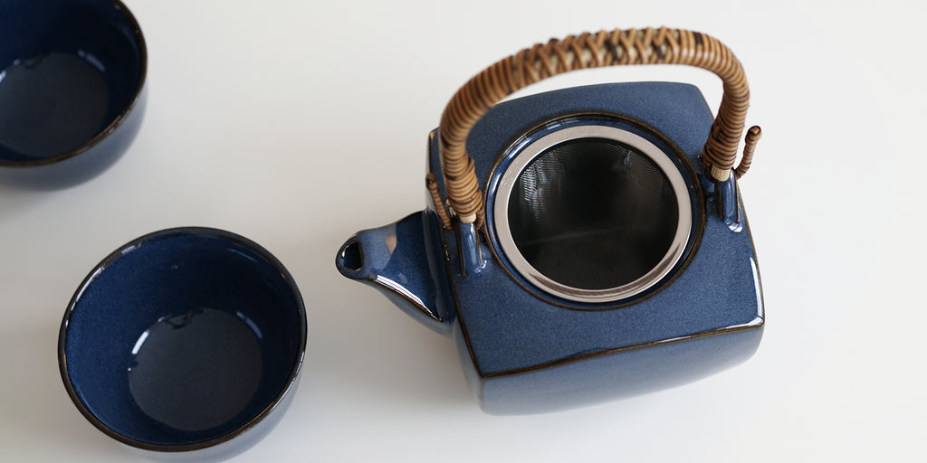 Top view of a dark blue ceramic teapot, showing the hand-wrapped bamboo handle and stainless steel infuser.