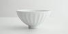 Side view of a white stoneware bowl with soft ridges radiating from the base on the outside.