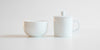 Side view of the competition brewing set. A white ceramic bowl on the left, and a white ceramic brewing vessel on the right.