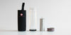 From left to right: a black cozy with a red logo to put the thermos in, the double-walled glass thermos, the stainless steel strainer basket, and the screw-on lid.