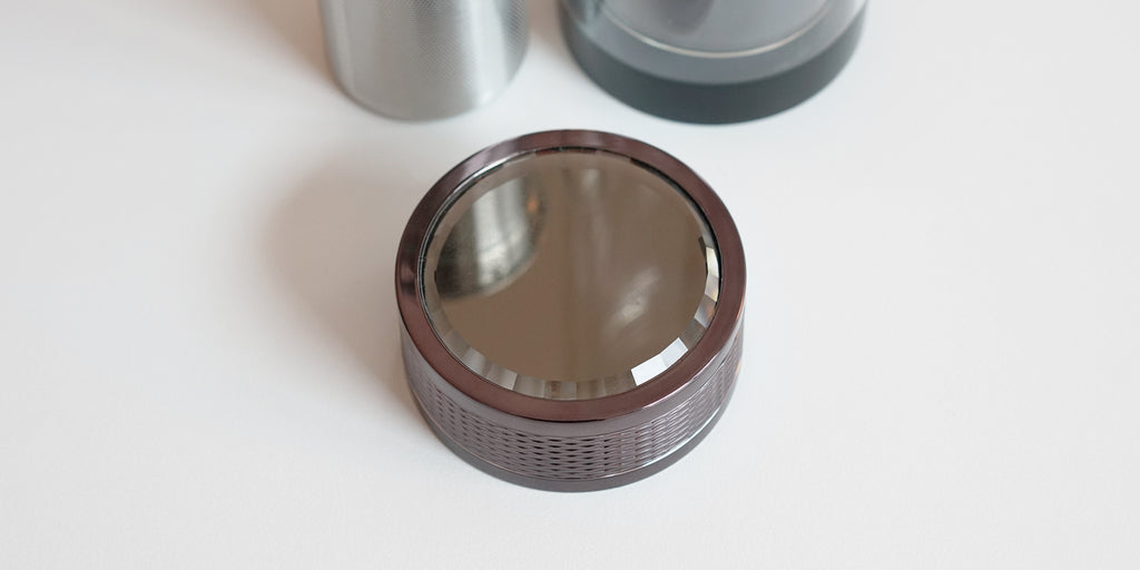Top down view of the top of the lid. It has subtle knurling around the outside to make it easier to grip, and a mirror on top.