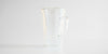 Rear view of the glass infuser cup, showing the handle. The infuser is in the cup, and the lid covers it.