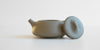 Side view of a gray duanni yixing teapot. The lid is facing the camera, resting against the handle.