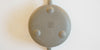 The bottom of a gray duanni yixing teapot, with three small feet around the base, and two maker's marks stamped into it, one in the middle of the base, and the other at the bottom of the handle.