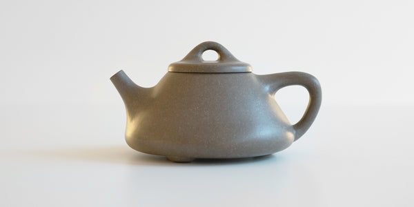 Side view of a gray duanni yixing teapot, showing its triangular shape.