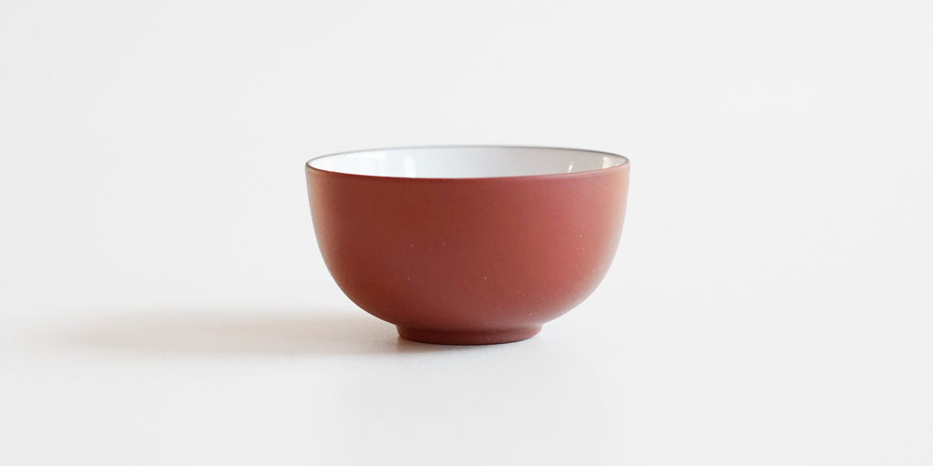 Side-view of a terracotta-colored teacup.