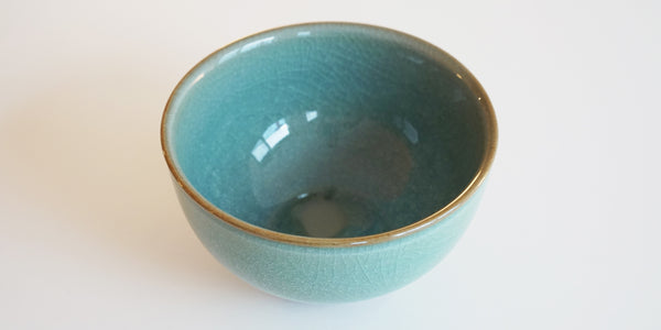 A top view of a Longquan-style celadon bowl, highlighting the faint craquelure patterns and light brown rim.