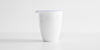 A tall white porcelain server, with a blue ring painted around the top edge and lip of the spout.