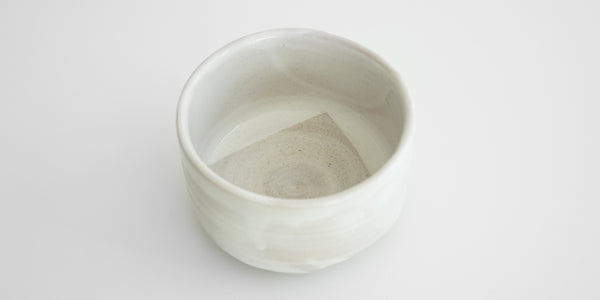 View of the inside of a straight-sided white bowl. The bottom has a light gray geometric pattern.