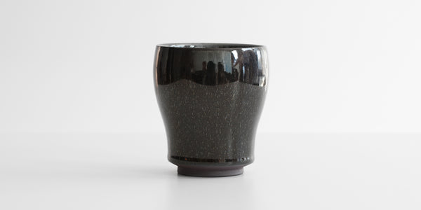 A side-view of a jian-ware cup, displaying the hare's fur texture on the otherwise black glaze.