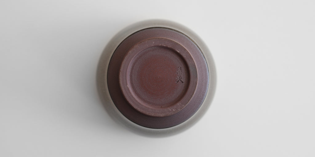 A top-down view of an upside-down jian-ware cup. The maker's mark of Xu Chun Tian is stamped into the unglazed base.