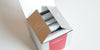 A silver box with 4 white bags of tea inside.