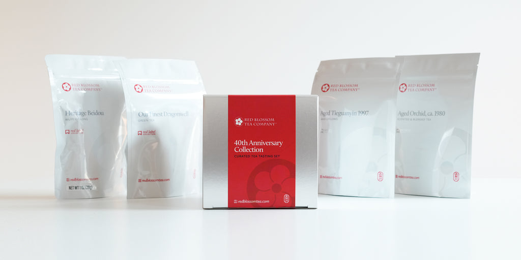 A silver box with a red label reading “40th Anniversary Collection”. Behind it are white bags of each of the teas in the collection,