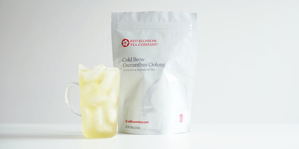A glass cup filled with ice and osmanthus oolong tea next to a package of Cold Brew Osmanthus Oolong.