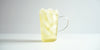 A glass cup filled with ice and osmanthus oolong tea on a white background.