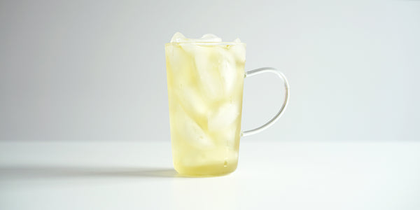 A glass cup filled with ice and osmanthus oolong tea on a white background.