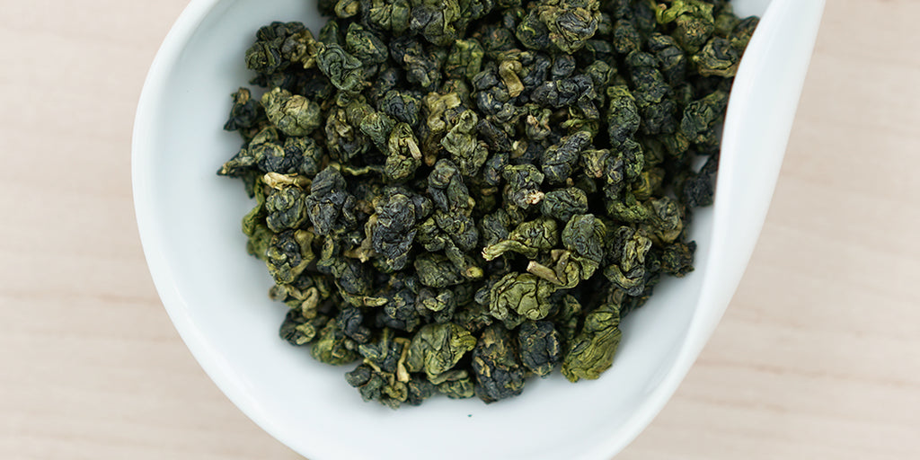 A white dish containing dry Formosa oolong tea leaves.