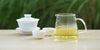 From left to right, a gaiwan, two teacups, and a glass server. The teacups and server have Formosa oolong tea in them.