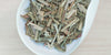 A white dish containing a blend of dry lemongrass and bits of ginger.