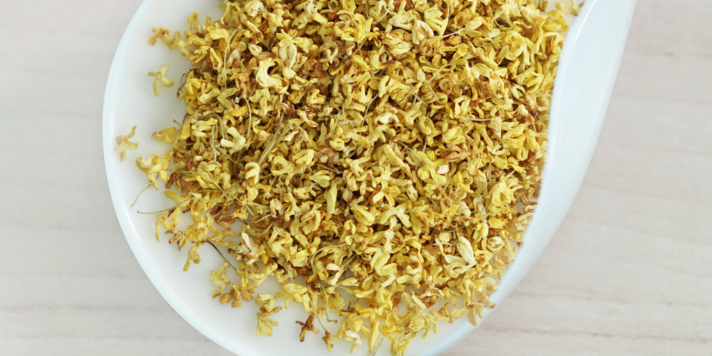 A white dish containing dry yellow osmanthus flowers.