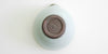 The bottom of a blue-green celadon shiboridashi, with Xu De Jia's maker's mark stamped into the unglazed base.