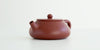 Front view of a terracotta-colored yixing pot highlighting the stout spout.