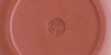 The bottom of a terracotta-colored yixing teapot. A maker’s mark is stamped into the base.