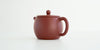 Rear view of a terracotta-colored yixing pot, highlighting the thin handle.