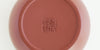 The bottom of a terracotta-colored yixing teapot. A maker’s mark is stamped into the base.