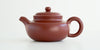 Side view of a terracotta-colored yixing pot, highlighting the ledged shape.