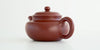 Rear view of a terracotta-colored yixing pot, highlighting the rounded handle.