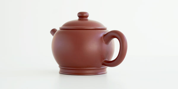 Rear view of a terracotta-colored yixing pot, highlighting the oval handle.