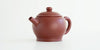 Front view of a terracotta-colored yixing pot highlighting the narrow spout.