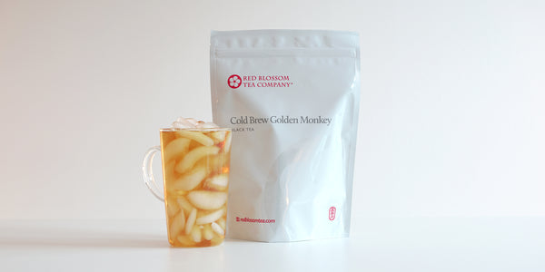 A glass cup filled with ice and black tea next to a package of Cold Brew Golden Monkey.