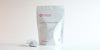 A large teabag filled with Phoenix oolong tea next to a package of Cold Brew Honey Orchid