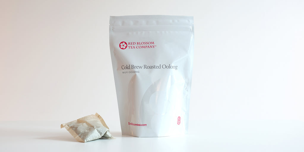 A large teabag filled with Wuyi oolong tea next to a package of Cold Brew Roasted Oolong