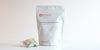 A large teabag filled with lychee-scented black tea next to a package of Cold Brew Summer Lychee