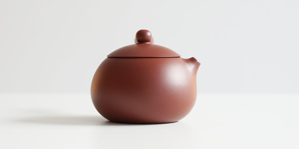 Side view of a terracotta-colored yixing pot, highlighting the round shape.