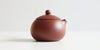 Side view of a terracotta-colored yixing pot, highlighting the round shape.