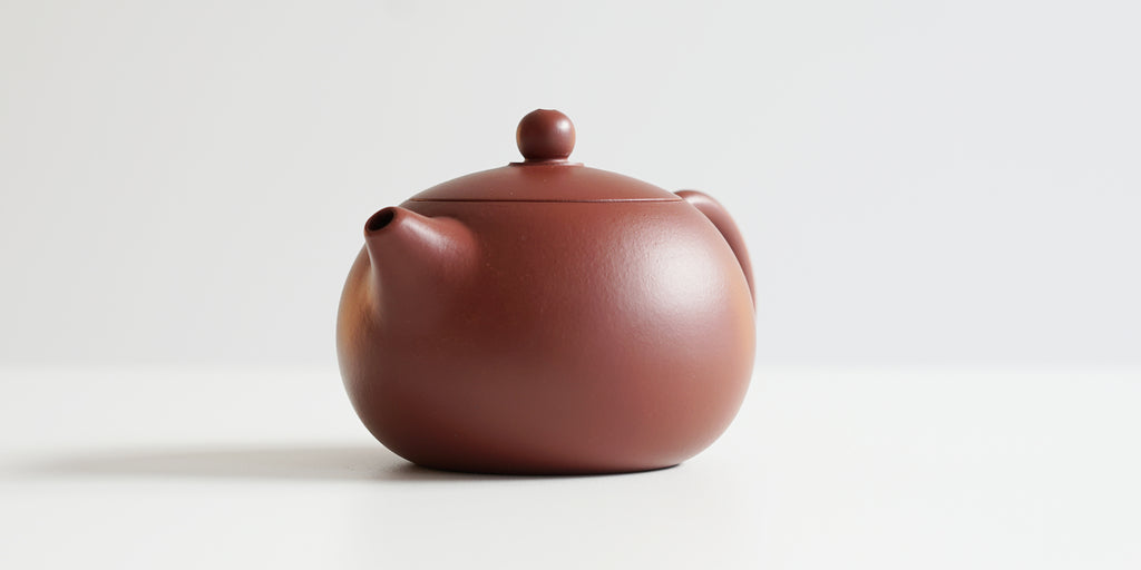 Front view of a terracotta-colored yixing pot highlighting the short spout.