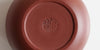 The bottom of a terracotta-colored yixing teapot. A maker’s mark is stamped into the base.
