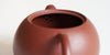 Rear view of the inside of a terracotta-colored yixing pot, showcasing the built-in filter made by punching small holes in the clay.