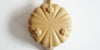 The bottom of a yellow yixing teapot. A maker’s mark is stamped into the base, and three hexagonal feet are around the outside.