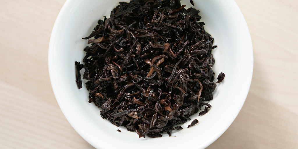 A top-down photo of brewed pu-erh tea leaves in a gaiwan.