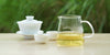 From left to right, a gaiwan, two teacups, and a glass server. The teacups and server have Formosa oolong tea in them.