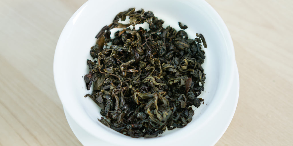 A top-down photo of brewed green tea leaves in a gaiwan.
