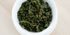 A top-down photo of brewed Formosa oolong tea leaves in a gaiwan.