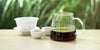 From left to right, a gaiwan, two teacups, and a glass server. The teacups and server have pu-erh tea in them.