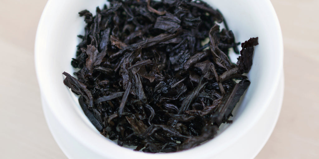 A top-down photo of brewed pu-erh tea leaves in a gaiwan.