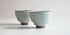 Side view of a pair of blue-green celadon teacups.